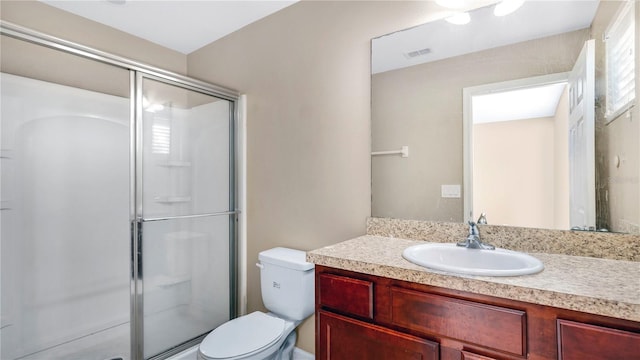 bathroom featuring vanity, toilet, and a shower with door