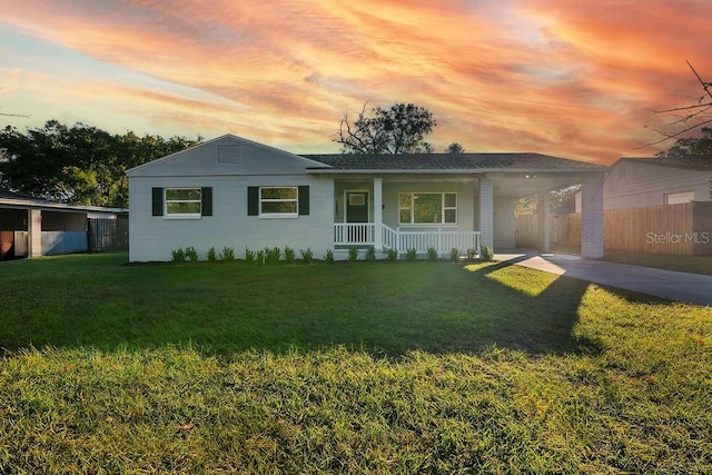 ranch-style home with a yard, a porch, and a carport