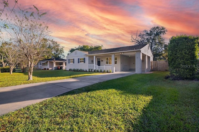 ranch-style house with a carport, covered porch, and a yard