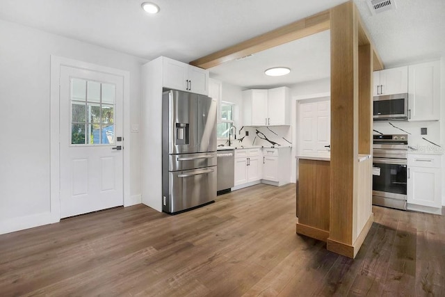 kitchen with white cabinetry, sink, dark wood-type flooring, tasteful backsplash, and appliances with stainless steel finishes