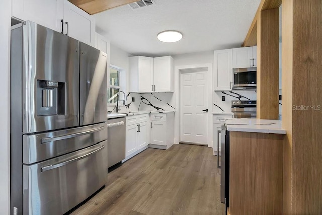 kitchen featuring sink, white cabinets, stainless steel appliances, and light wood-type flooring