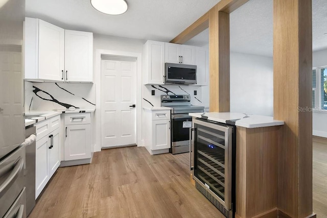 kitchen featuring wine cooler, white cabinetry, and appliances with stainless steel finishes