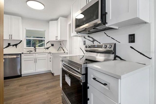 kitchen featuring sink, dark hardwood / wood-style floors, decorative backsplash, appliances with stainless steel finishes, and white cabinetry