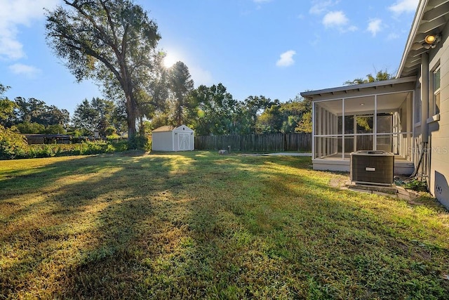 view of yard with central air condition unit, a sunroom, and a storage shed