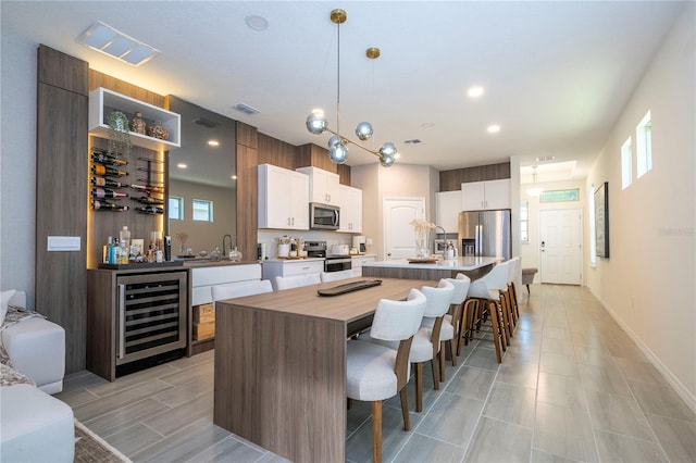 kitchen with a center island, a healthy amount of sunlight, wine cooler, decorative light fixtures, and appliances with stainless steel finishes