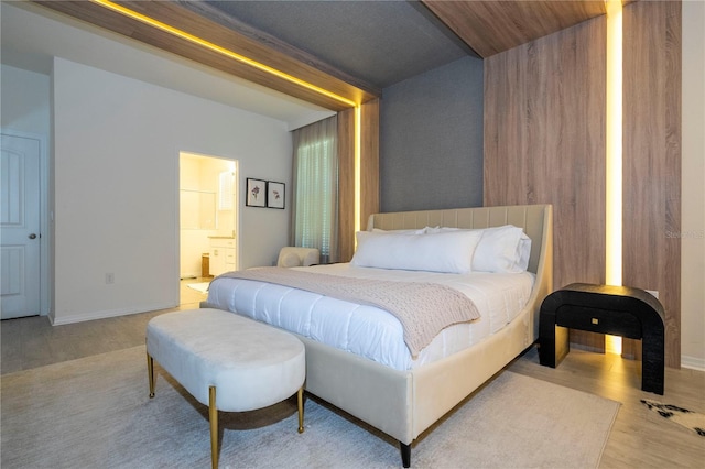 bedroom with ensuite bath and light hardwood / wood-style flooring