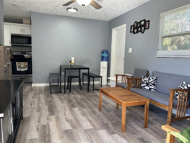 living area featuring a textured ceiling, light hardwood / wood-style floors, and ceiling fan