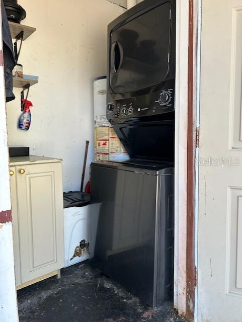 clothes washing area with stacked washing maching and dryer