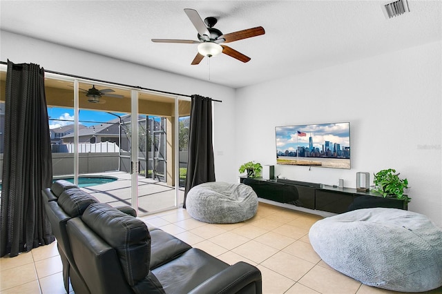 living room with a textured ceiling, ceiling fan, and light tile patterned flooring