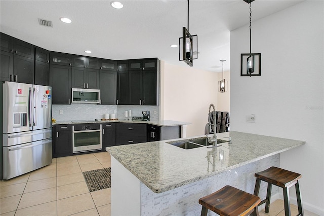 kitchen featuring sink, a breakfast bar area, decorative light fixtures, kitchen peninsula, and stainless steel appliances