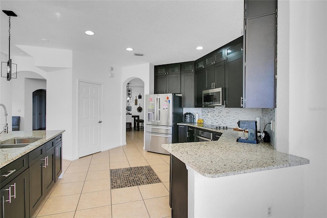 kitchen featuring hanging light fixtures, light tile patterned floors, light stone countertops, appliances with stainless steel finishes, and kitchen peninsula