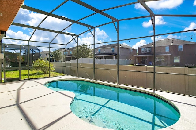 view of pool with glass enclosure and a patio