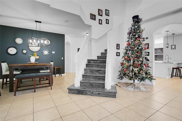 staircase with tile patterned floors, sink, a high ceiling, and a notable chandelier