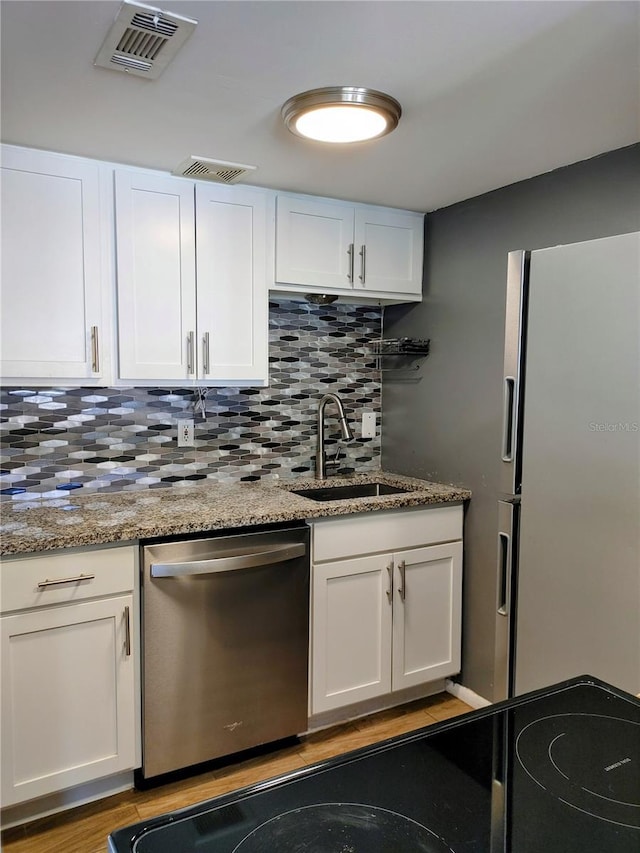 kitchen featuring dishwasher, refrigerator with ice dispenser, white cabinetry, and sink