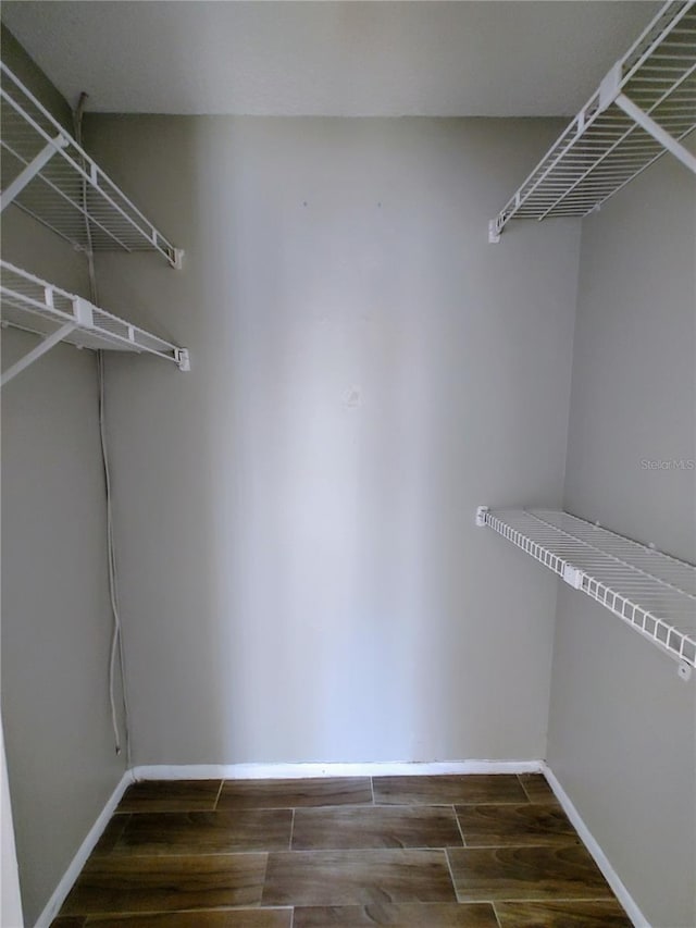 walk in closet with dark hardwood / wood-style flooring