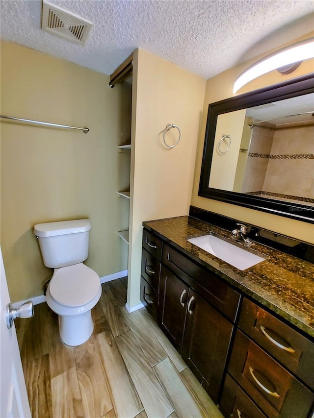 bathroom with hardwood / wood-style flooring, vanity, toilet, and a textured ceiling