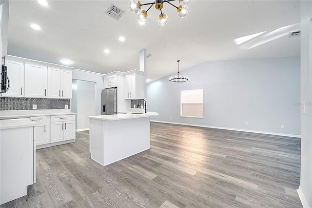 kitchen featuring hanging light fixtures, stainless steel fridge with ice dispenser, a chandelier, vaulted ceiling, and white cabinets