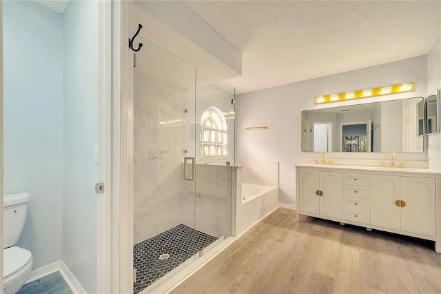 full bathroom with plus walk in shower, a textured ceiling, toilet, vanity, and hardwood / wood-style flooring