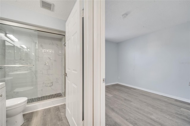 bathroom with walk in shower, vanity, a textured ceiling, hardwood / wood-style floors, and toilet