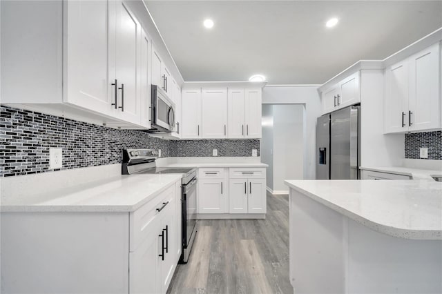 kitchen with kitchen peninsula, decorative backsplash, stainless steel appliances, light hardwood / wood-style flooring, and white cabinets