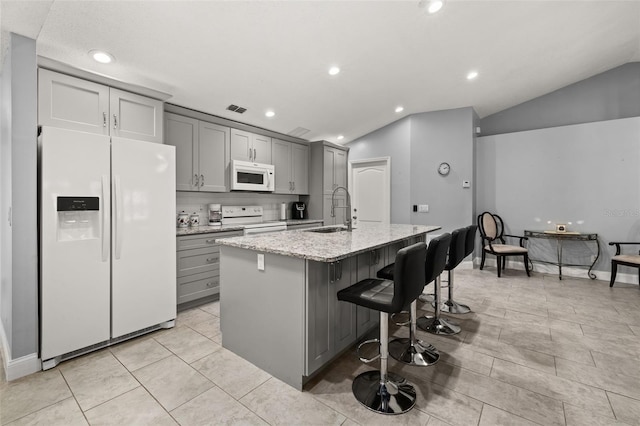 kitchen with gray cabinetry, sink, vaulted ceiling, white appliances, and a kitchen island with sink