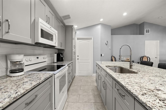 kitchen with sink, light stone counters, lofted ceiling, white appliances, and decorative backsplash