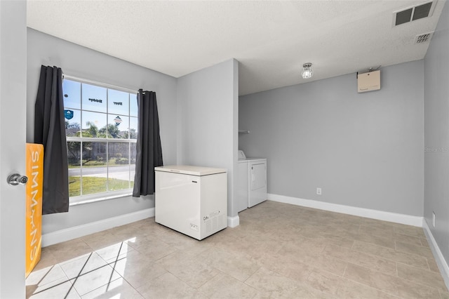 laundry room with separate washer and dryer, a textured ceiling, and light tile patterned floors