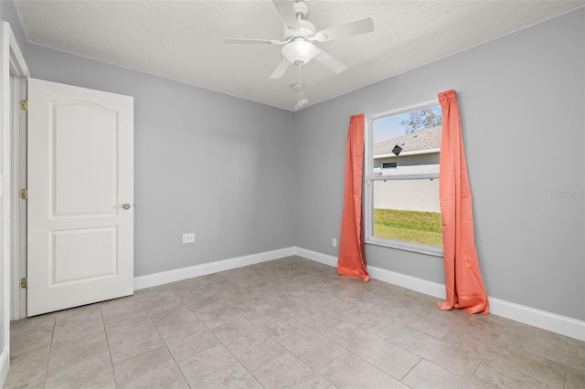 unfurnished room with ceiling fan, light tile patterned flooring, and a textured ceiling