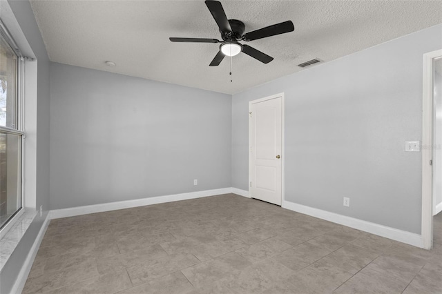 tiled spare room with ceiling fan and a textured ceiling