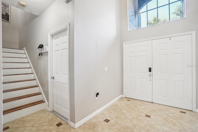 foyer entrance with light tile patterned floors and a textured ceiling