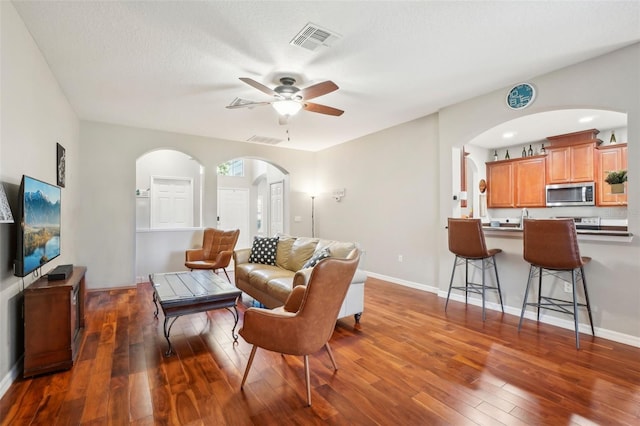 living room featuring ceiling fan, dark wood-type flooring, and a textured ceiling