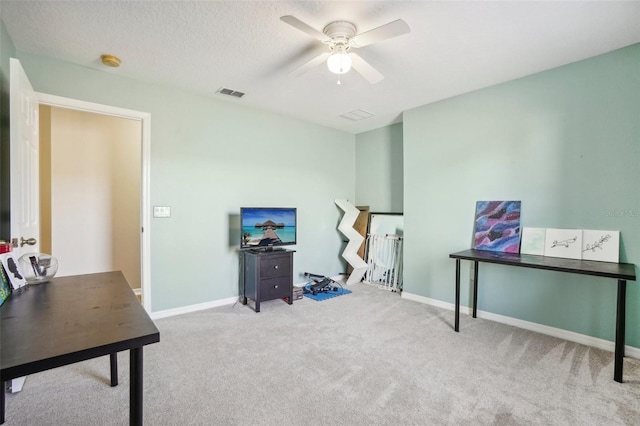 carpeted office with a textured ceiling and ceiling fan