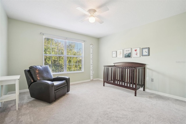 bedroom with light carpet, ceiling fan, and a nursery area