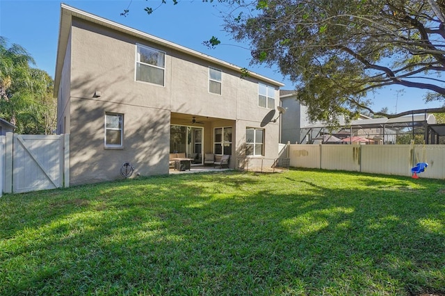 rear view of property with a patio area, ceiling fan, and a yard