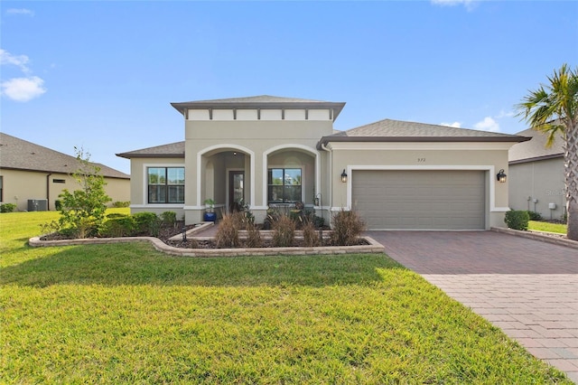 view of front of house with central AC unit, a garage, and a front lawn