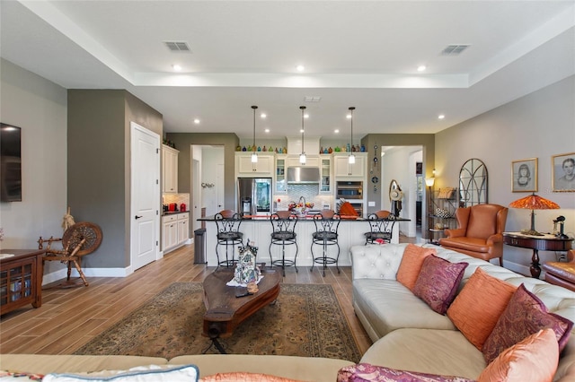 living room with a tray ceiling and wood-type flooring