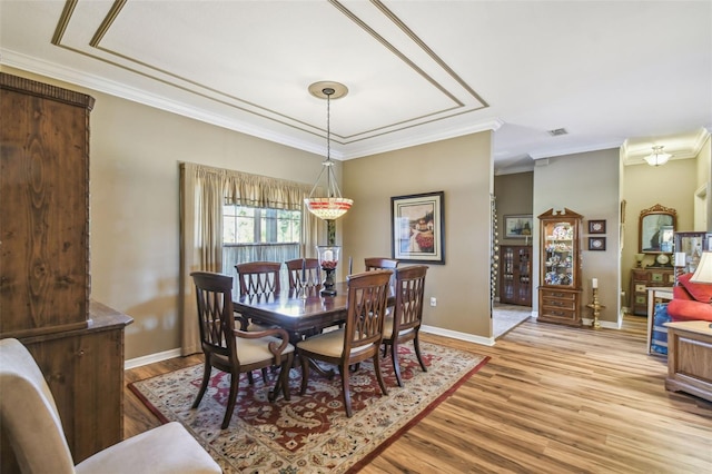 dining space with light hardwood / wood-style floors and ornamental molding