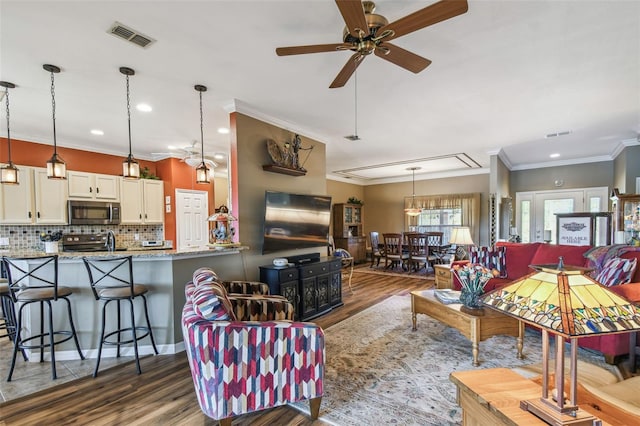 living room featuring dark hardwood / wood-style flooring, ceiling fan, and crown molding