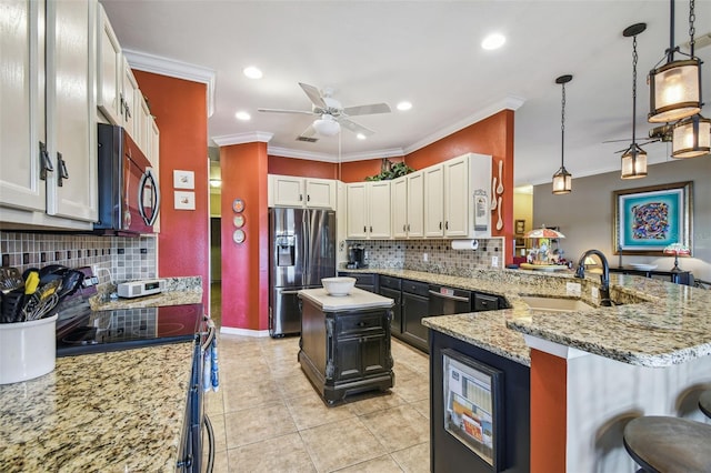 kitchen with appliances with stainless steel finishes, a kitchen island, sink, pendant lighting, and white cabinetry