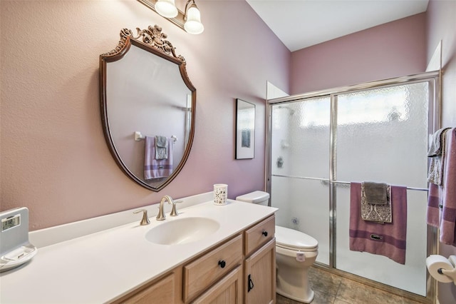 bathroom with tile patterned flooring, vanity, a shower with shower door, and toilet