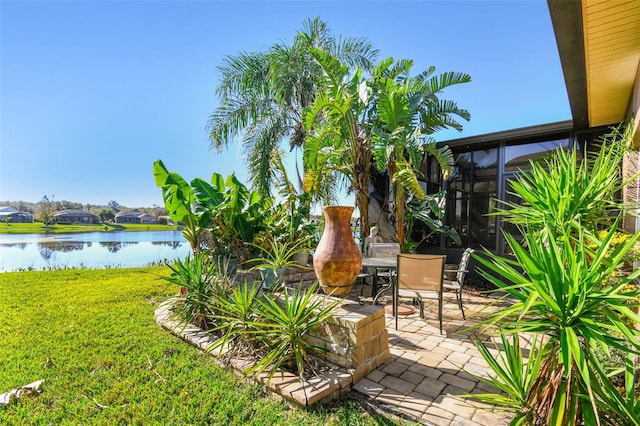 view of yard with a water view, a patio area, and a sunroom