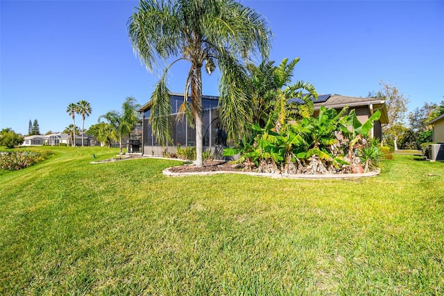 view of yard with central AC unit and a lanai