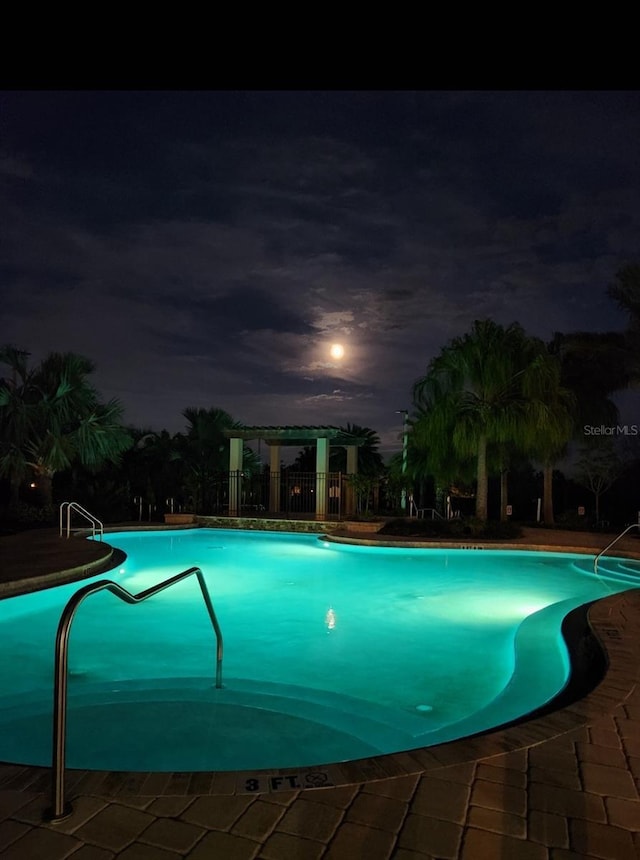 pool at twilight featuring a patio area