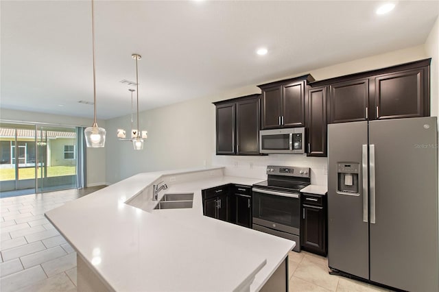 kitchen with pendant lighting, sink, light tile patterned floors, appliances with stainless steel finishes, and kitchen peninsula