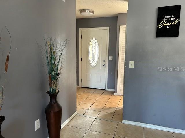 foyer entrance with a textured ceiling and light tile patterned flooring