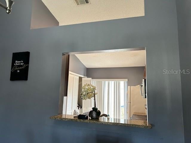 corridor featuring a textured ceiling and vaulted ceiling