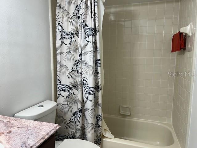 full bathroom featuring vanity, shower / bath combination with curtain, and toilet