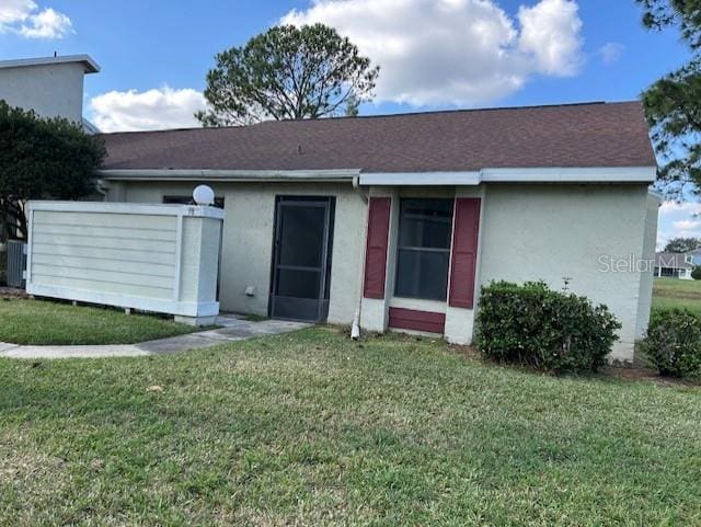 back of house with a yard and stucco siding