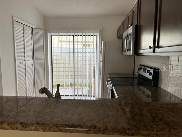 kitchen with stainless steel appliances, dark brown cabinets, backsplash, and a wealth of natural light