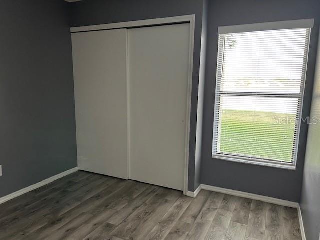 unfurnished bedroom with baseboards, a closet, and wood finished floors